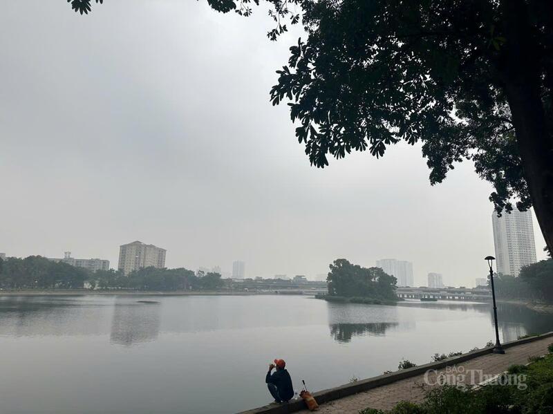 Người dân ngồi bên hồ Linh Đàm trong buổi sáng mù sương, bầu trời xám xịt do ô nhiễm không khí sáng 3/12.
