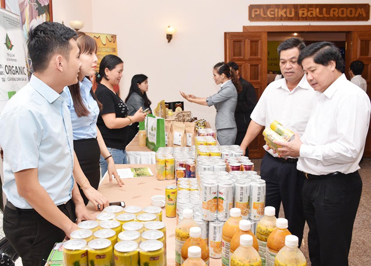 Thứ trưởng Bộ Nông nghiệp và PTNT Lê Quốc Doanh (bìa phải) và Phó Chủ tịch UBND tỉnh Kpă Thuyên xem sản phẩm chanh dây của Công ty DOVECO. Ảnh: Lê Nam