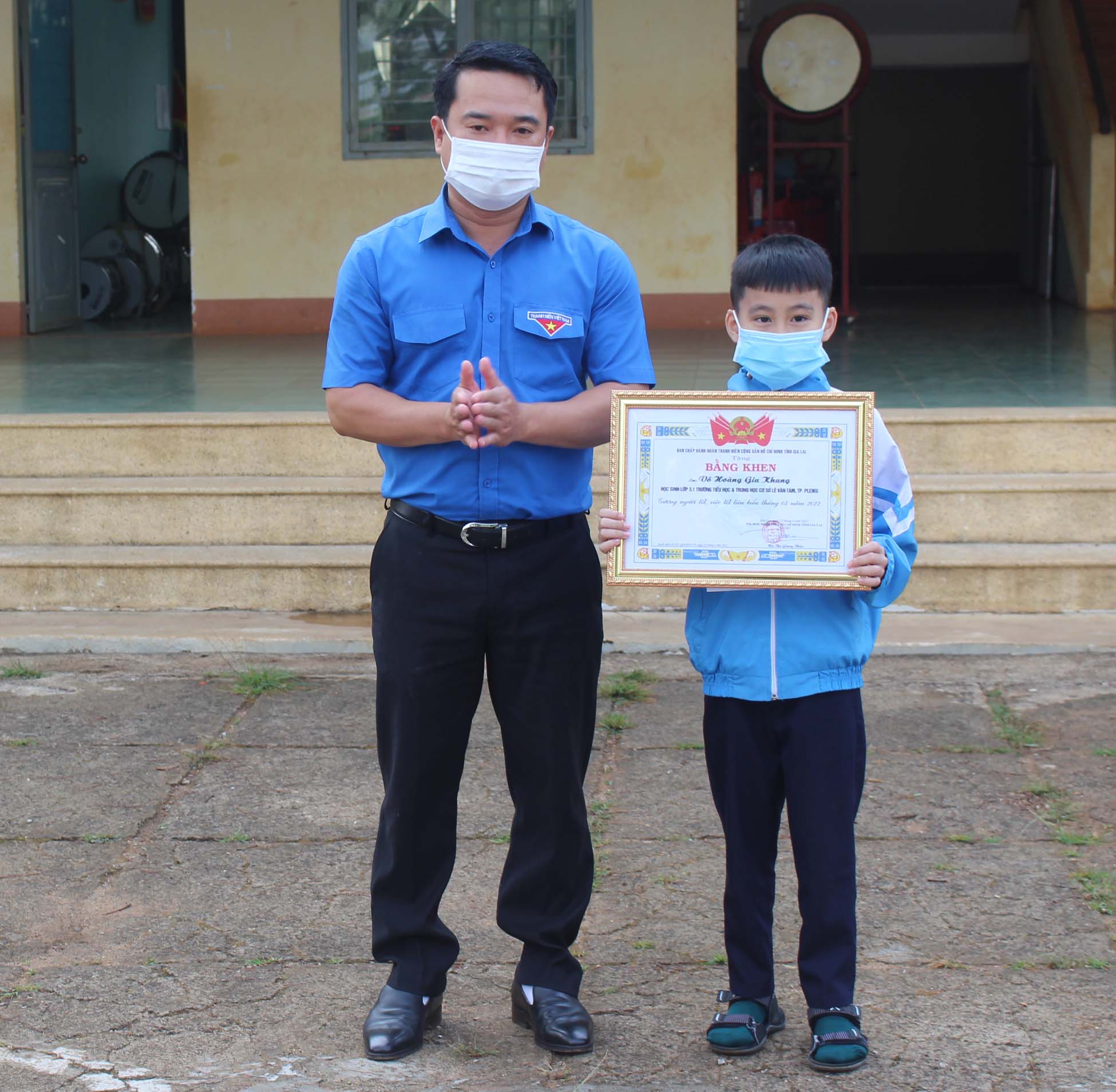 Anh Đỗ Duy Nam (bìa trái)-Phó Bí thư Tỉnh Đoàn, Chủ tịch Hội đồng Đội tỉnh tặng bằng khen gương người tốt-việc tốt cho em Võ Hoàng Gia Khang. Ảnh: Phan Lài