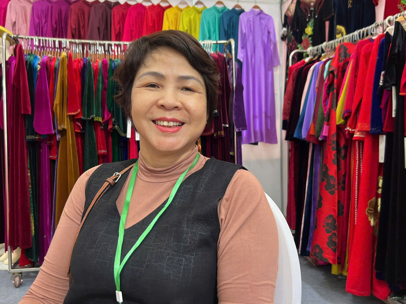 Bà Vũ Thị Hoa Lý, nhân viên Công ty TNHH Thời trang Hoàng Ly Fashion chia sẻ về thương hiệu áo dài truyền thống phục vụ du khách tới mua sắm tại hội chợ. Ảnh: Thanh Thảo
