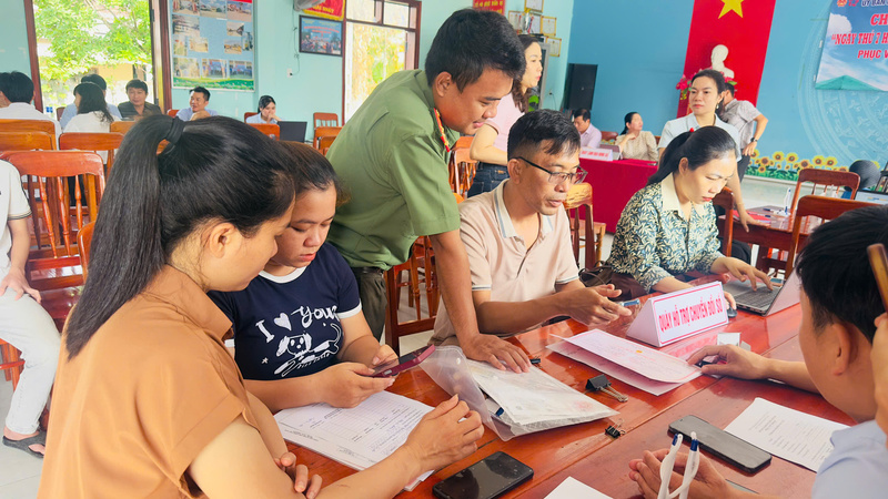 Những ngày cuối tuần, tổ hành chính lưu động lại tranh thủ hướng dẫn giúp người dân làm giấy tờ. Ảnh: Tuệ Lâm